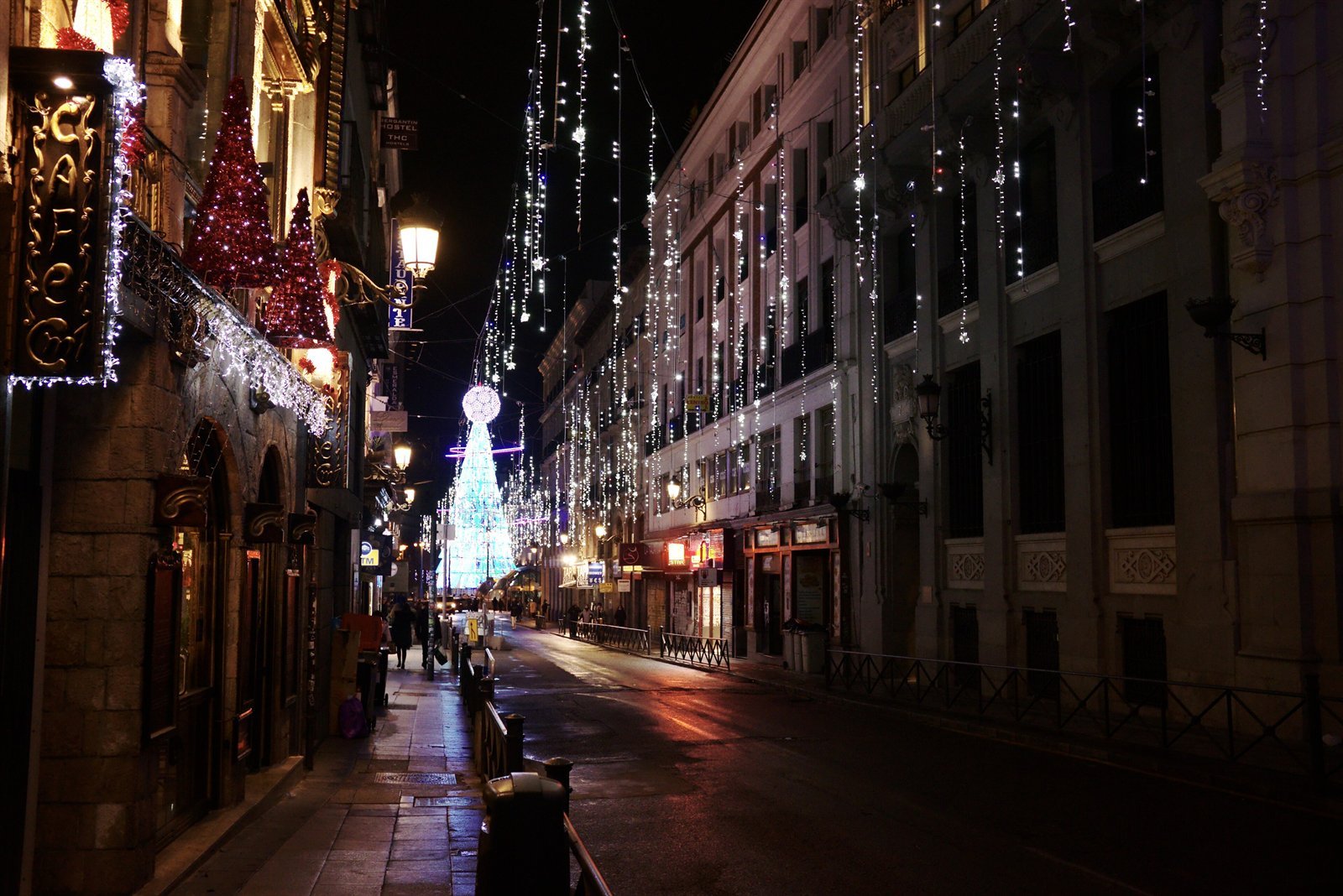 A street in central Madrid with lights and an illuminated Christmas tree